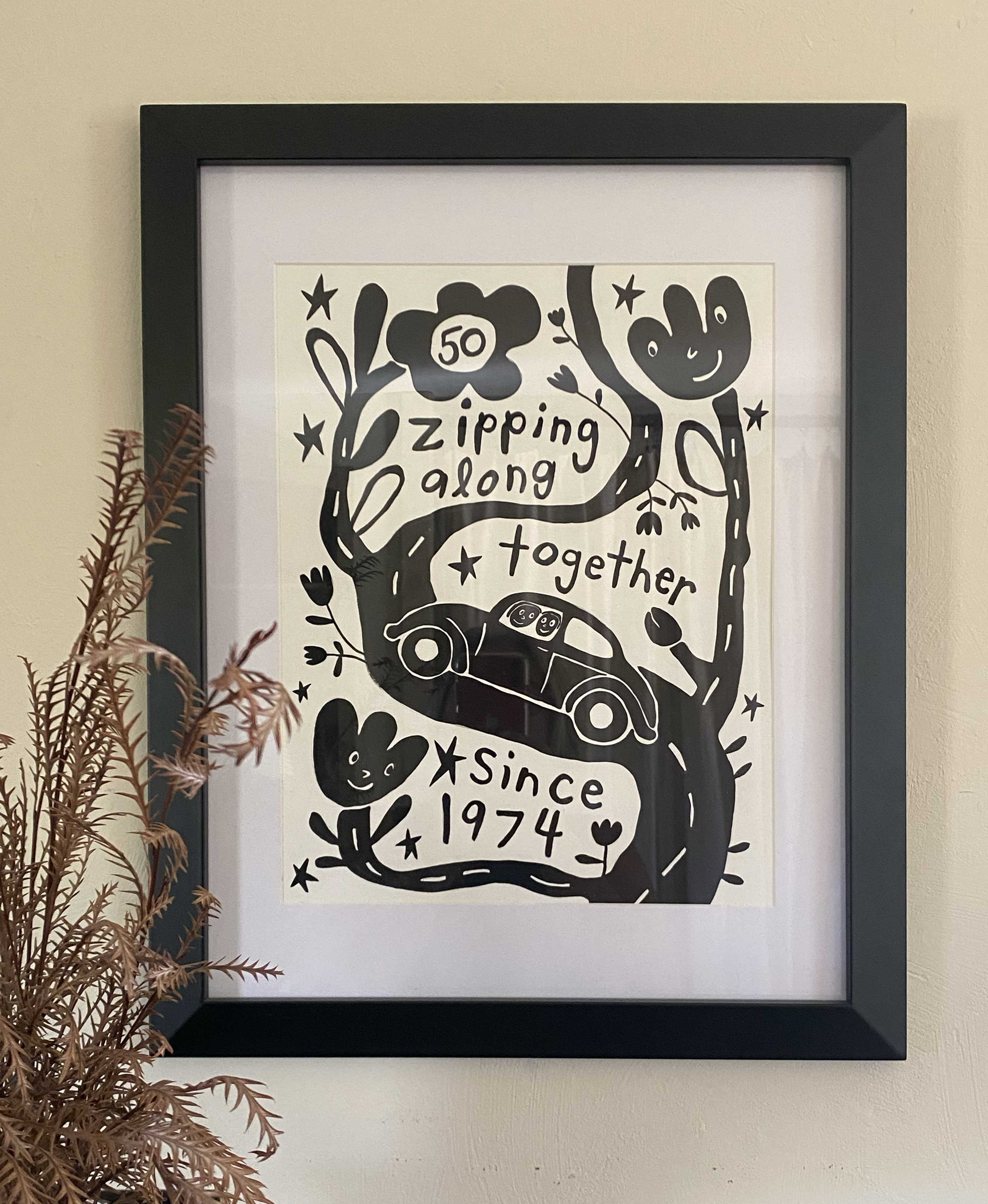 Framed artwork with black and white design of a car and text on a beige wall.